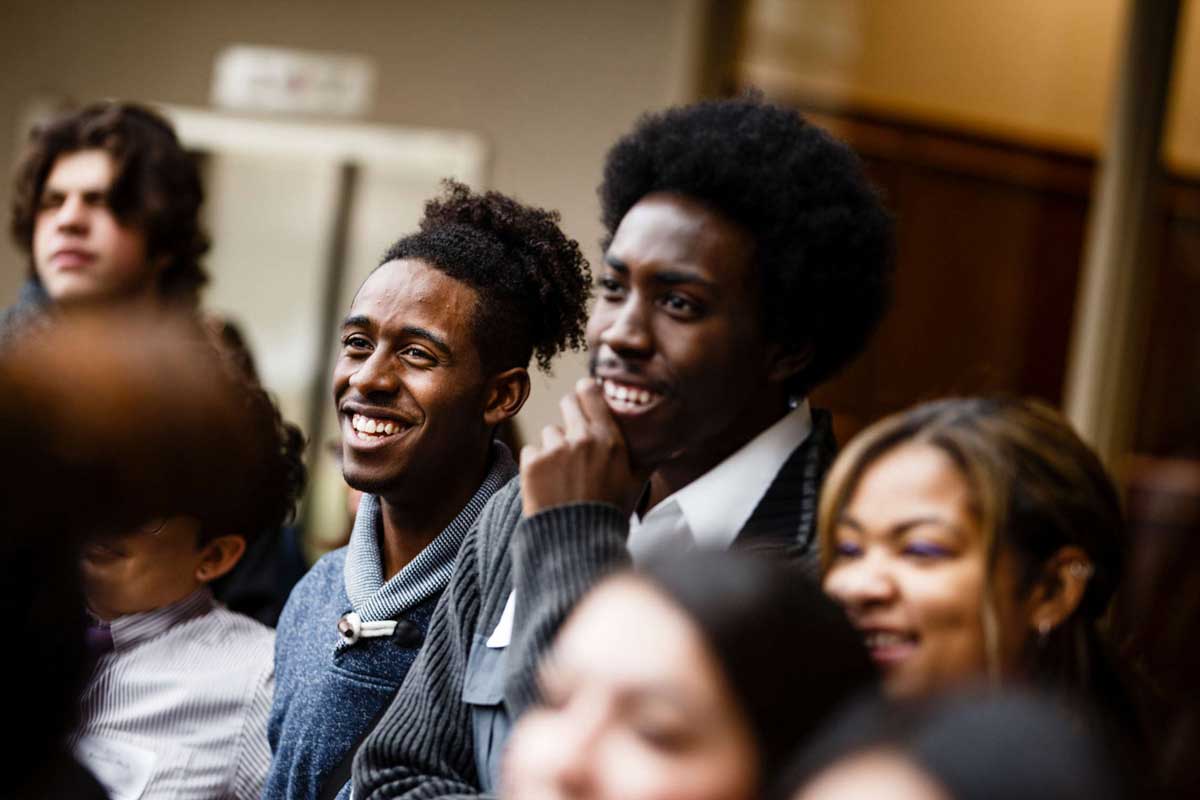 Three smiling DFC students in crowd at dedication event.